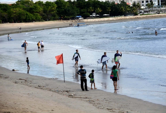 Potret turis asing asyik berjemur dan berselancar di Pantai Kuta