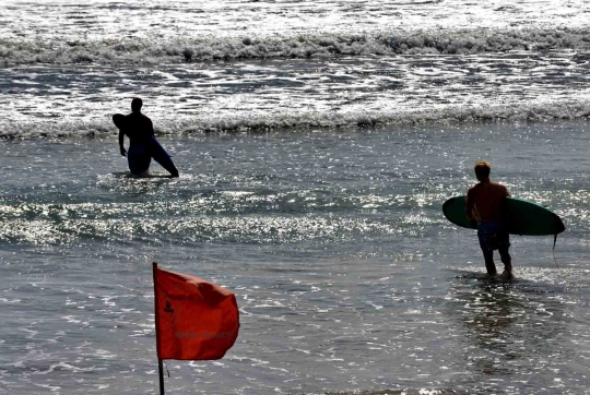 Potret turis asing asyik berjemur dan berselancar di Pantai Kuta