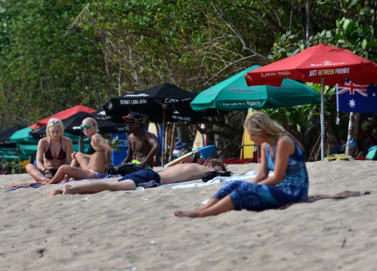 Potret turis asing asyik berjemur dan berselancar di Pantai Kuta