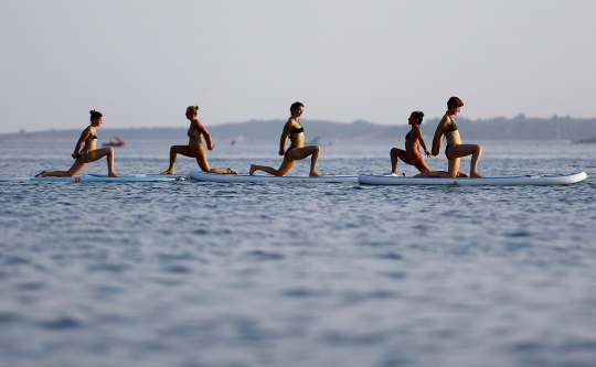 Aksi wanita berbikini latihan yoga di atas Laut Adriatik