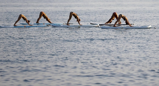 Aksi wanita berbikini latihan yoga di atas Laut Adriatik