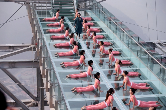 Aksi wanita-wanita seksi berlatih yoga di lantai kaca tepi jurang