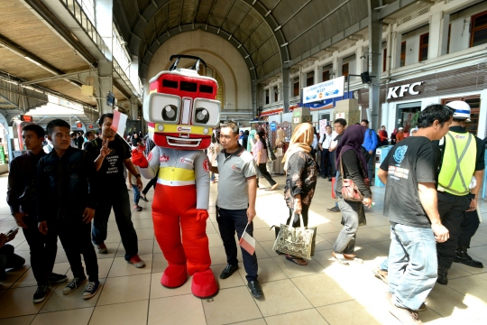 Aksi maskot KRL bagi-bagi bendera ke penumpang