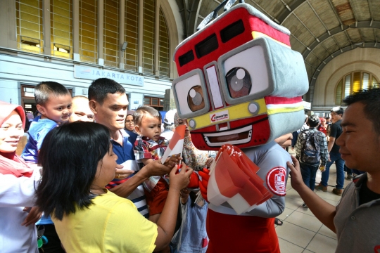 Aksi maskot KRL bagi-bagi bendera ke penumpang