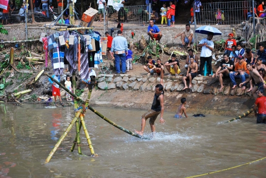 Keseruan lomba panjat pinang di atas aliran Kalimalang