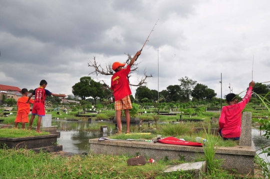 Keseruan anak-anak memancing di tengah kuburan Tanah Kusir