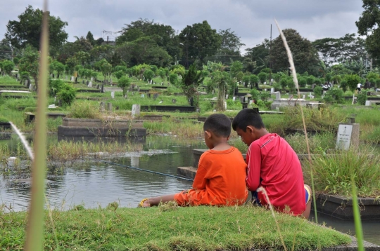 Keseruan anak-anak memancing di tengah kuburan Tanah Kusir