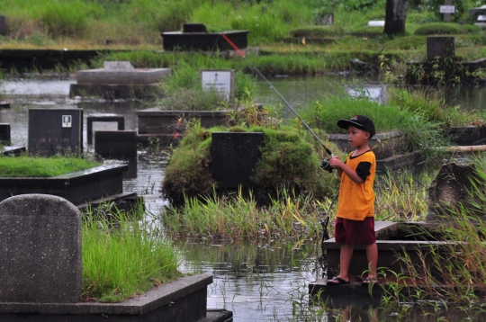 Keseruan anak-anak memancing di tengah kuburan Tanah Kusir