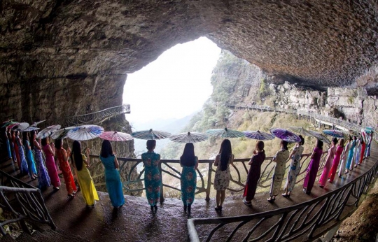 Aksi wanita berkostum tradisional pose di tebing Gunung Jinfo