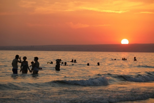 Berenang sambil menikmati keindahan sunset di pantai Italia