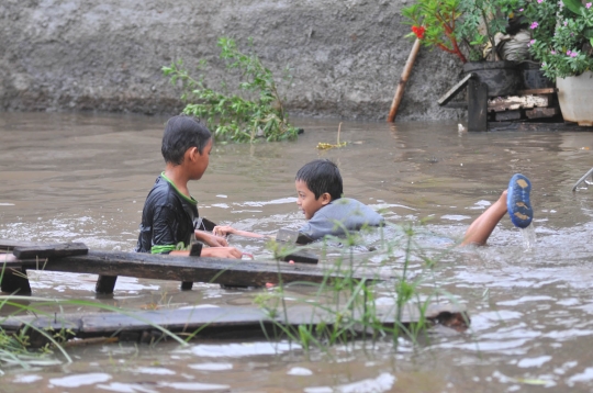 Keceriaan anak-anak bermain di tengah banjir Jati Padang