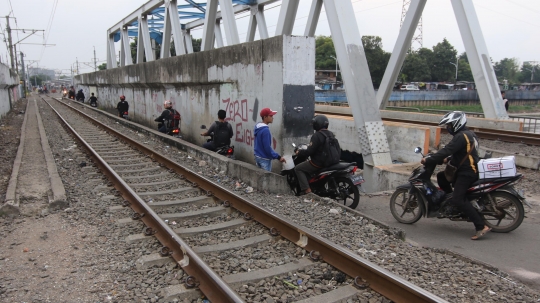 Nekatnya pemotor lewati jalanan mepet rel kereta di Kanal Banjir Barat