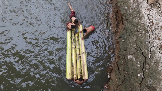 Potret anak-anak main rakit di Sungai Ciliwung tanpa alat keselamatan