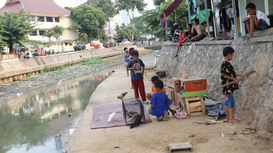 Tunggu waktu buka puasa, anak-anak bermain di bantaran Ciliwung