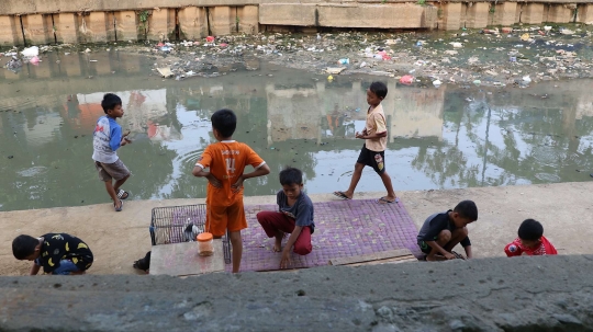 Tunggu waktu buka puasa, anak-anak bermain di bantaran Ciliwung