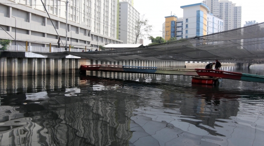 Kali dekat Wisma Atlet Kemayoran ditutup kain hitam untuk kurangi bau