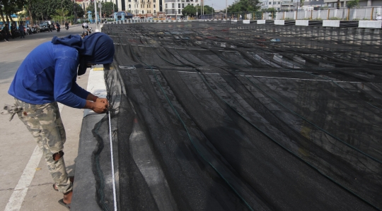 Kali dekat Wisma Atlet Kemayoran ditutup kain hitam untuk kurangi bau