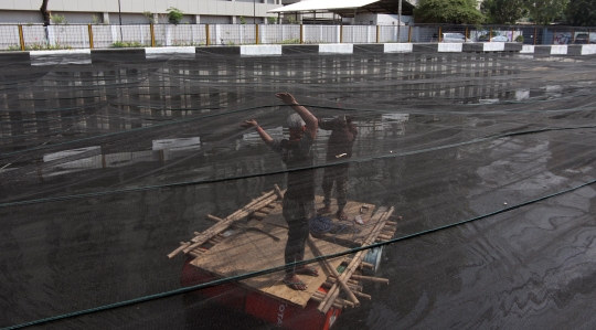 Kali dekat Wisma Atlet Kemayoran ditutup kain hitam untuk kurangi bau