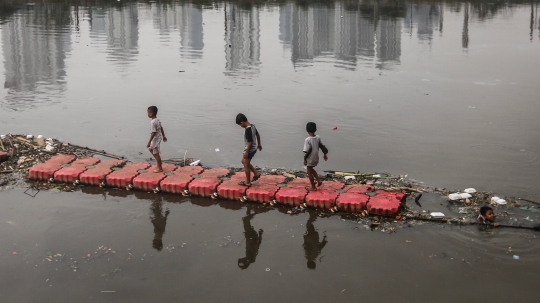 Keceriaan Anak-Anak Bermain di Tepi Sungai Banjir Kanal Barat