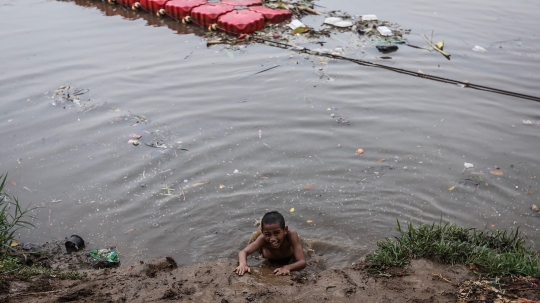 Keceriaan Anak-Anak Bermain di Tepi Sungai Banjir Kanal Barat