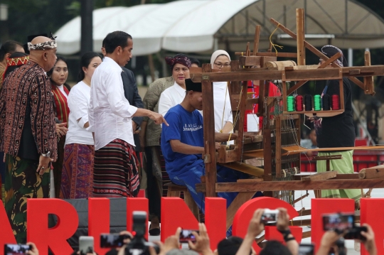 Aksi Jokowi Jajal Alat Tenun di Festival Sarung Indonesia 2019