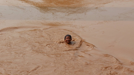 Kenekatan Anak-anak Berenang di Sungai Ciliwung yang Meluap