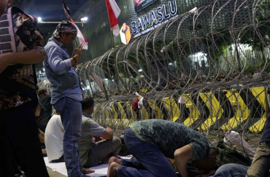 Massa Buka Puasa dan Salat Maghrib di Depan Kawat Berduri Bawaslu