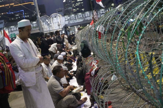 Massa Buka Puasa dan Salat Maghrib di Depan Kawat Berduri Bawaslu