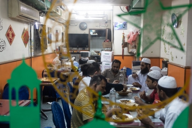 Para imigran asal Pakistan menikmati makan sahur sebelum berpuasa di distrik Kwai Chung, Hong Kong, pada 25 Mei 2019.