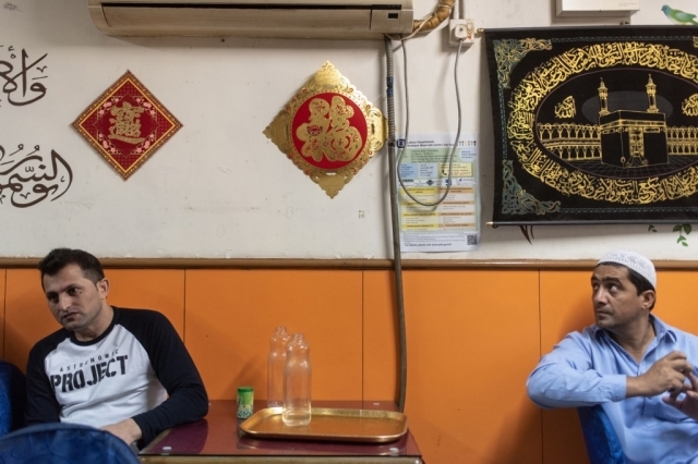 Dua imigran asal Pakistan duduk di sebuah restoran di distrik Kwai Chung, Hong Kong, pada 25 Mei 2019.
