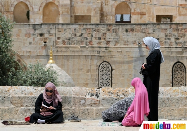 Tiga wanita muslim berdoa pada hari Jumat terakhir di bulan suci Ramadan di depan Kubah Batu, Yerusalem (31/5).