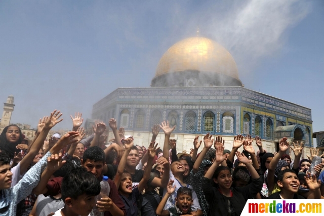 Ekspresi anak-anak Palestina yang terlihat bahagia saat mendapat semprotan air dari seorang pemuda yang sedang mendinginkan suasana sebelum melaksanakan salat Jumat terakhir di bulan suci Ramadan di dekat Kubah Batu, Yerusalem (31/5).
