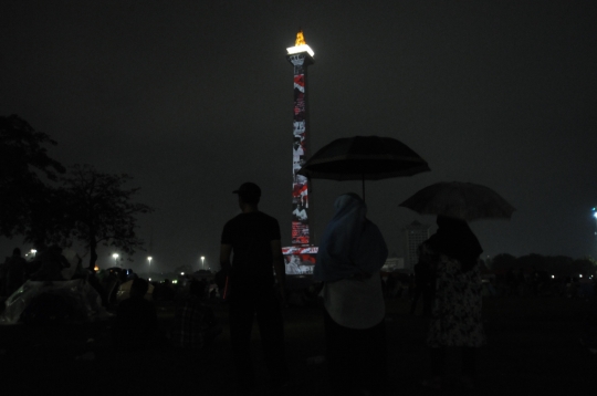 Hujan, Warga Tetap Antusias Saksikan Video Mapping Tahun Baru 2020 di Monas