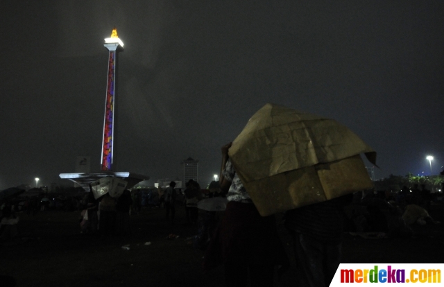 Foto Hujan Warga Tetap Antusias Saksikan Video Mapping Tahun Baru 2020 Di Monas Merdeka Com