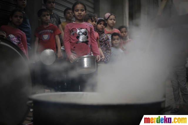 Sejumlah anak mengantre untuk mendapatkan sop yang dibagikan gratis kepada warga miskin selama Ramadan di Jalur Gaza, Palestina, pada 24 April 2020.
