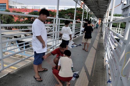 Potret Anak-Anak Ibu Kota Bermain Layangan di JPO