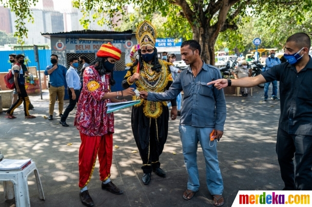 Seorang petugas dari Kantor Kehakiman yang berpakaian seperti penguasa kematian dan keadilan Hindu, Dewa Yamraj memberikan denda kepada pelanggar karena tidak mengenakan masker di tempat umum di New Delhi, Senin (28/9/2020). Petugas mengingatkan masyarakat untuk mengenakan masker sebagai tindakan pencegahan terhadap virus corona Covid-19 di tempat umum.