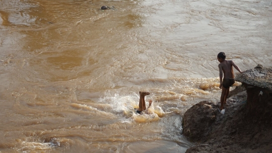 Kenekatan Anak-Anak Berenang di Tengah Aliran Deras Sungai Ciliwung