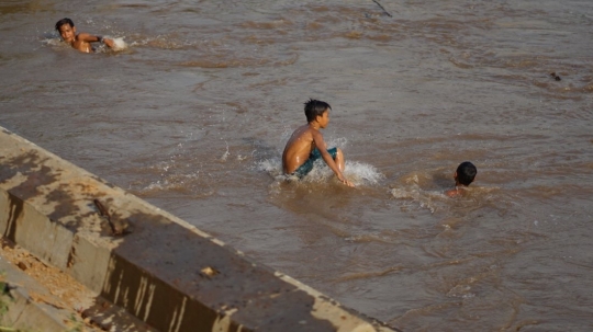 Kenekatan Anak-Anak Berenang di Tengah Aliran Deras Sungai Ciliwung