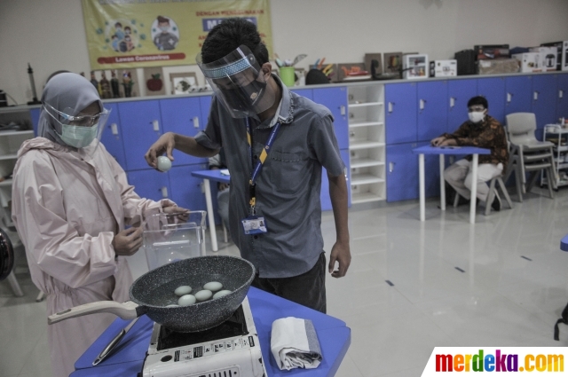 Terapis atau pengajar membimbing mahasiswa berkebutuhan khusus merebus telur asin saat kelas terapi mata kuliah wirausaha di Lembaga Pendidikan dan Keterampilan Kampusnya Manusia, Kranggan, Bekasi, Jawa Barat, Kamis (3/12/2020). Kelas terapi untuk mahasiswa berkebutuhan khusus di Kampusnya Manusia rutin dilakukan dua kali dalam seminggu yang bertujuan meningkatkan kecerdasan motorik dan verbal serta mengembangkan kemampuan berwirausaha.