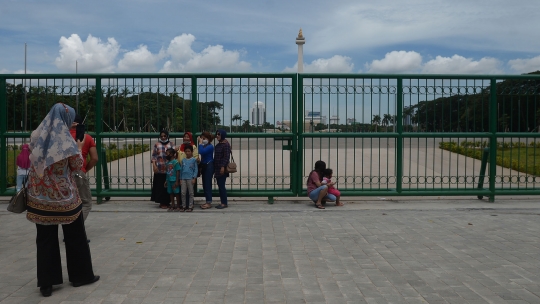 Belum Dibuka, Warga Berfoto di Balik Pagar Monas