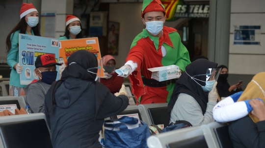 Berbaju Santa, Petugas KAI Bagikan Masker ke Penumpang