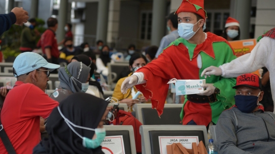 Berbaju Santa, Petugas KAI Bagikan Masker ke Penumpang