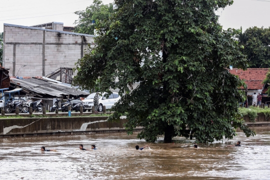 Aksi Nekat Anak-Anak Lompat ke Sungai Ciliwung yang Meluap
