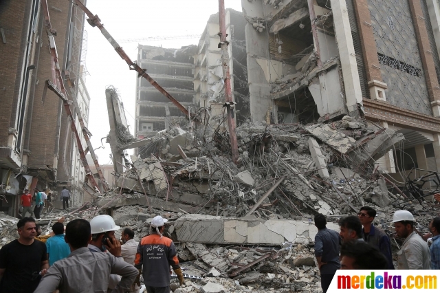 Tim penyelamat melakukan pencarian korban di antara reruntuhan gedung di Abadan, Iran, pada 23 Mei 2022. Gedung 10 lantai yang merupakan perumahan dan komersial runtuh sebagian pada Senin (23/5). Sebanyak 11 orang dilaporkan tewas, sementara sekitar 80 orang terjebak di bawah puing-puing.