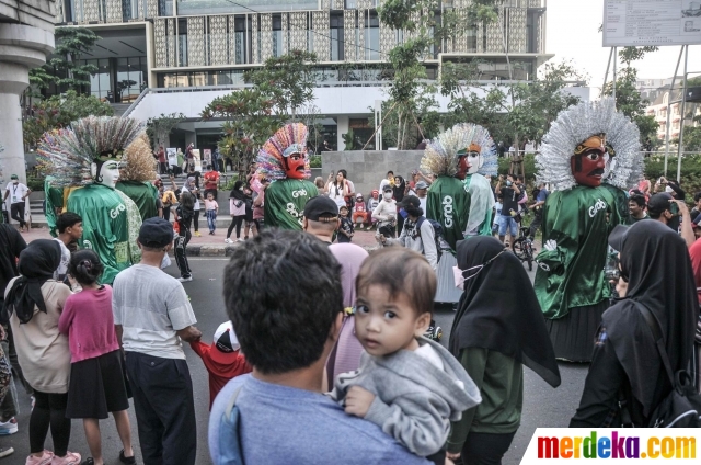 Warga saat menyaksikan pawai kesenian Betawi di Jalan MH Thamrin, Jakarta, Minggu (19/6/2022). Pawai yang menampilkan berbagai budaya dan kesenian Betawi seperti ondel-ondel, tari topeng, serta tanjidor tersebut digelar dalam rangka menyambut HUT ke-495 DKI Jakarta.
