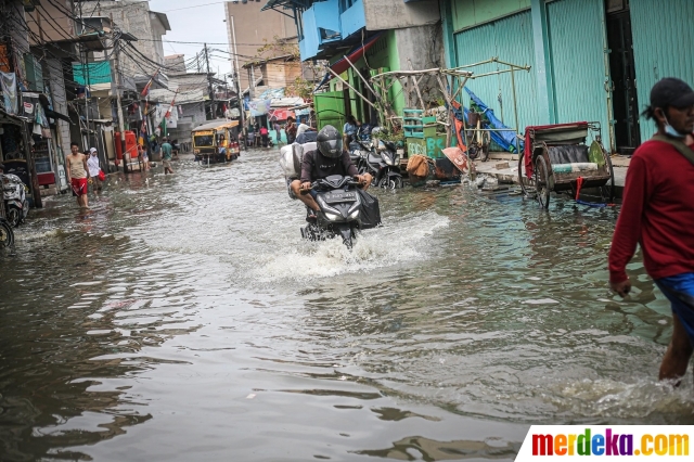 Pengendara sepeda motor melintasi genangan banjir rob yang menerjang kawasan Muara Angke, Jakarta, Jumat (25/11/2022).