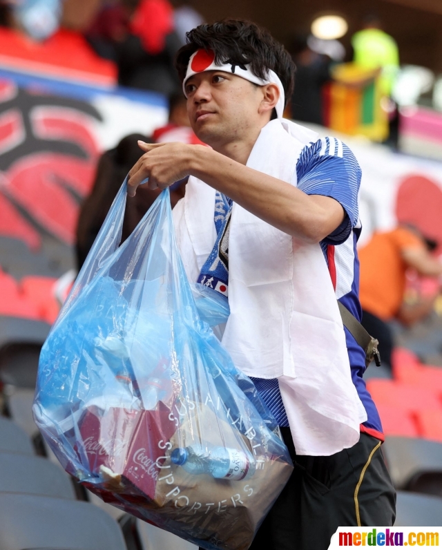 Aksi suporter timnas Jepang saat memungut sampah yang berserakan di tribun usai pertandingan timnas negaranya yang melawan Kosta Rika pada laga grup E Piala Dunia 2022 di Ahmad Bin Ali Stadium, Al Rayyan, Qatar, Minggu (27/11/2022).