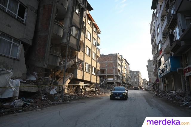 Sebuah mobil melintas di antara reruntuhan bangunan saat melewati jalan di Hatay, Turki, Selasa (7/3/2023). Satu bulan pasca gempa bumi berkekuatan magnitudo 7,8 mengguncang sebagian besar Turki pada 6 Februari 2023 yang menewaskan lebih dari 46.000 jiwa.