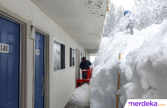 Warga menggunakan mesin membersihkan gundukan salju yang nyaris menutupi sebuah motel saat badai salju terus turun di pegunungan Sierra Nevada.